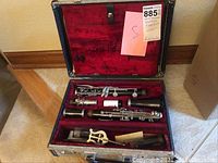 Open case showing disassembled clarinet pieces and accessories laid out in red velvet interior
