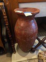 Full view of large terra cotta vase showing the whole shape and size relative to surrounding objects.
