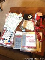 Photo of multiple music education items including instruction books, erasable music slates, a black clock, a red handheld cassette player or microphone with red coiled cord, and guitar straps.