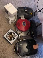Lot overview showing coffee maker, quesadilla makers, electric casseroles, and hot plates