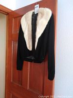 Black jacket with removable white fur collar hanging, showing overall appearance.