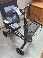 Full view of knee scooter showing handlebars, knee rests, frame, and mesh basket.