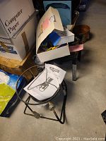 Photo showing the outdoor turkey fryer base on the floor with a small white box placed on top containing assorted kids toys.