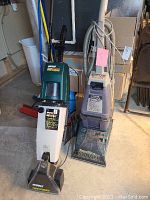 Photo showing both carpet cleaners side by side in a basement, displaying overall condition and size.