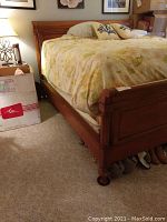 Side view of assembled wooden sleigh bed frame showing headboard, side rails, and part of mattress