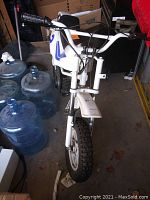 Front view showing handlebars, front fork and wheel, number plate and part of seat