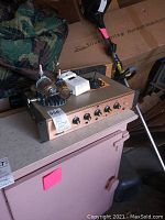 Raymer amplifier with multiple control knobs on front panel, sitting on a surface next to a camouflage blanket.