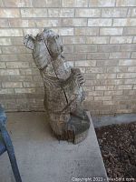 Side view of carved wooden bear statue showing upright posture and weathered wood cracks.