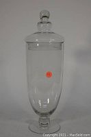 Front view of clear glass vase with lid, showing overall shape and design.