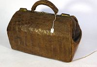 Front-side view showing the crocodilian textured leather body and the curved handle of the vintage doctor's bag.