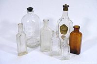 Photo showing seven vintage bottles: six clear and one brown, with various shapes and sizes including one with a Colgate's Cashmere Bouquet label.