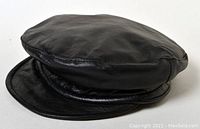 Front angled view of the black lambskin leather cap showing the rounded crown and brim