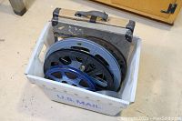 Box containing eight movie reels of different sizes and materials, showing the entire lot and packaging.