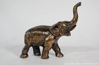 Side view of metal elephant figurine showing textured body and raised trunk.