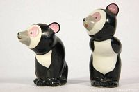 Front view of two ceramic bear salt and pepper shakers, showing black and white colors with pink accents on ears and eyes.