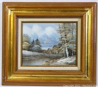 Framed small oil painting showing overall scene of snow covered landscape with water and trees, good condition.