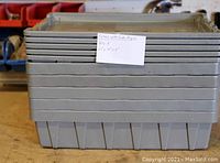 Stack of five gray rigid plastic totes with lids visible, showing size and condition