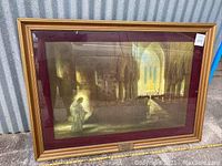 Frontal view of vintage framed church interior print in a golden gilt frame with burgundy mat, showing the figure holding a book and interior light details.