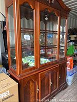 Full view of wood china cabinet with three glass doors and lower storage doors, showing scuffs and scratches on wood surfaces.