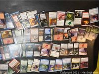 Photo showing a variety of Magic the Gathering cards laid out on a surface, showing different card backs and faces with various characters and spell types.