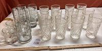 Side view of the full set of 18 vintage clear cut glass drinkware showing different sizes and cut glass designs.
