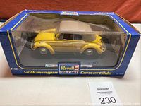 Yellow Volkswagen Beetle convertible in original blue Revell display box with clear front window. Box shows visible signs of wear and dirt accumulation, as noted by seller.