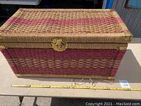 Front and top view of vintage woven wicker trunk showing the pink and natural color pattern and metal latch closure.