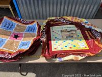 Two large deflated inflatable pieces: one is a Scrabble game board and the other a tile holder with score spaces and a black star center.
