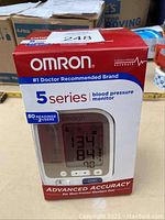 Front view of unopened Omron 5 Series blood pressure monitor box with image of device and sample readings