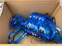 16 new blue safety goggles with clear lenses and black adjustable straps in a cardboard box.