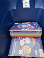 Brightly colored construction paper packs stacked in blue tub