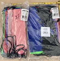 Two unopened plastic bags each containing a large drawstring backpack by Oriental Trading Company in multiple colors including pink, blue, and black.
