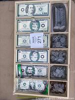 Top view of wooden play money tray with compartments containing stacks of play bills and plastic coins.