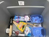 Lot of office and craft supplies showing stapler, rulers, scissors, markers, glue gun, and miscellaneous small items in blue plastic containers.