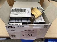 Box containing eight Master Lock V Line 4140KA padlocks, showing one padlock and keys on top of the box.