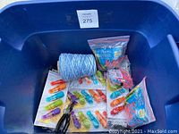 Blue bin holding blue and white twine roll, large colorful clips, packaged Brites Tie Bands rubber bands