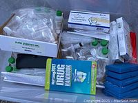 Wide view of bin with water testing containers, medical vials, and book