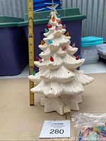 Full view of white ceramic Christmas tree with colored bulbs and silver star, shown next to ruler for scale about 14 inches tall.