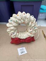 Front view of vintage ceramic Christmas wreath light with red bow base and multicolored bulbs embedded on wreath surface