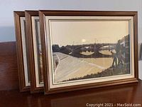 View of the three framed prints together showing the wood frames and glass fronts with the seen bridge and river artwork.