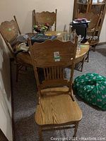 Four vintage oak pressback chairs around a table, showing overall set and style.