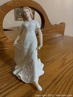 Front and angled view of Royal Doulton Friendship figurine on wooden surface with mirror behind reflecting figurine's back showing the details of the dress and figure.