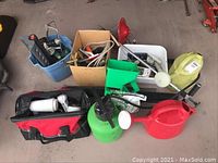 Overview of the garden tools and supplies including watering cans, sprayers, tool bags, and various garden tools grouped on floor.