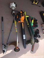 Five tools laid out: Stihl string trimmer head, Poulan Pro blower, Ryobi trimmer shaft, Black & Decker hedge trimmer housing, and ratchet straps