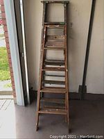 Front view of shorter wooden step ladder with paint marks and wear