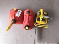 Yellow McCulloch Mini Mac 25 chainsaw with two red gas cans placed on floor, items viewed from top