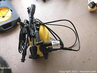 Top-down angled view of the yellow Karcher pressure washer showing hoses and attachments coiled and mounted on the unit.