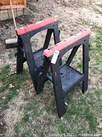 Two plastic folding sawhorses standing on grass outside, showing side and top views.