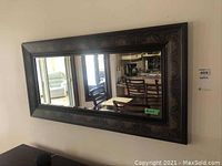 Front view of rectangular wall mirror showing reflective surface and decorative patterned frame.