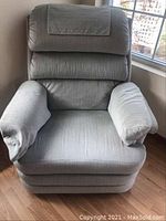 Front view of pale blue-green upholstered La-Z-Boy recliner rocker chair with plush cushions and padded armrests.